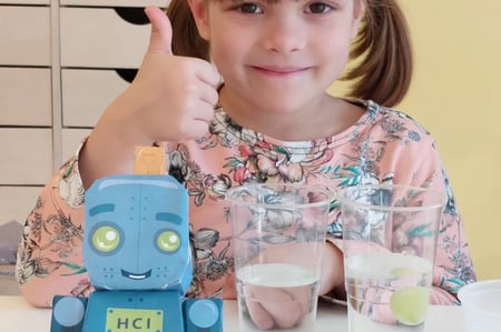 Preschooler giving thumbs up after conducting floating grapes activity