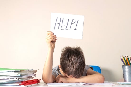 An image of a student holding up a "Help" sign with his face down