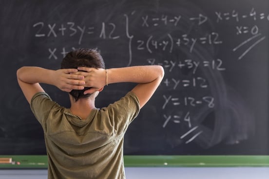 Student is in distress as he faces chalkboard covered with math problems