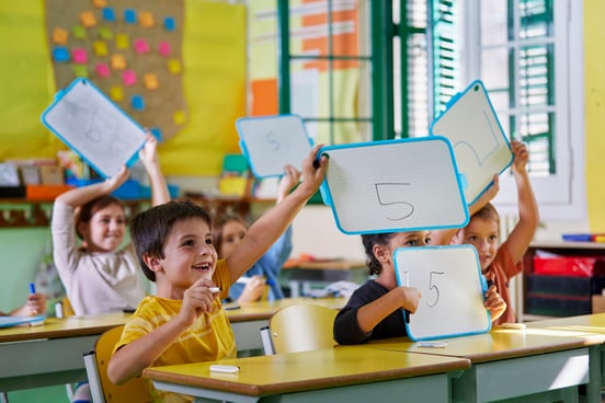 Students holding up whiteboards in math class