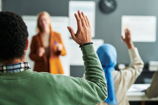 Students raising hands in an inquiry-based classroom