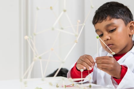 Young learner building a structure with toothpicks and dried peas