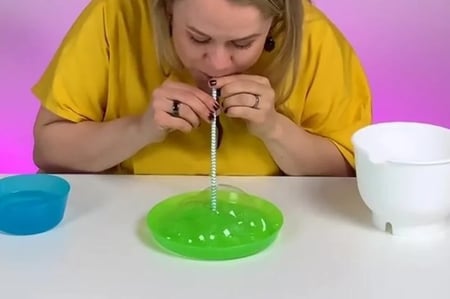 Using straw to blow bubbles in a plate